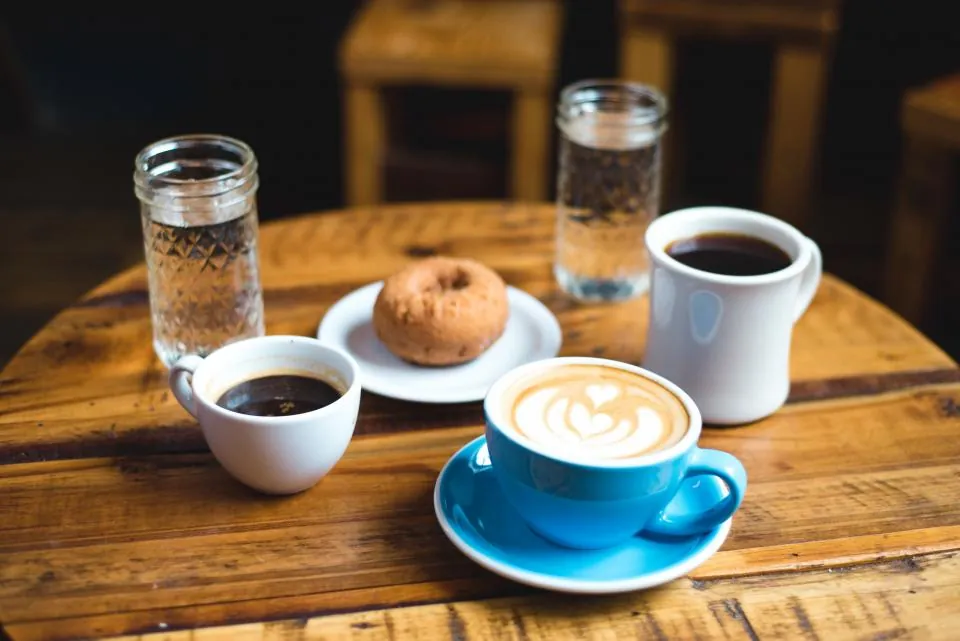 Meja kayu dengan cangkir kopi dan buku catatan